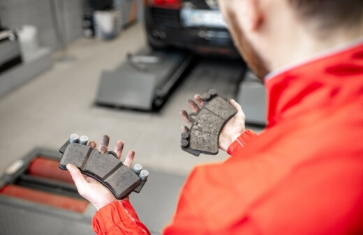 A brake specialist compares a new and worn out brake pad, emphasising the need for timely brake repairs and mobile brake replacement services