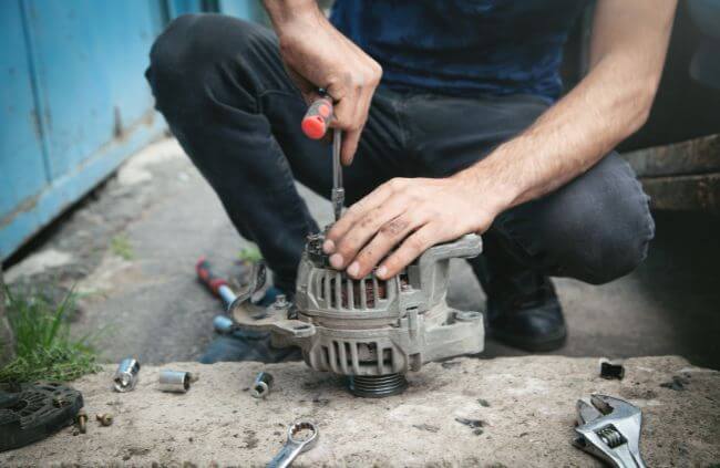 Mobile mechanic performing car alternator repair with tools during on-site alternator replacement service in Sydney